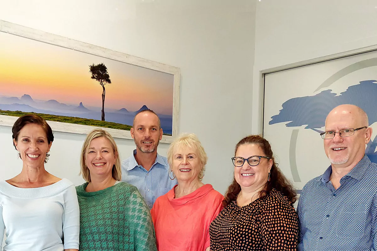 The MdW team standing in their office in front of some artwork