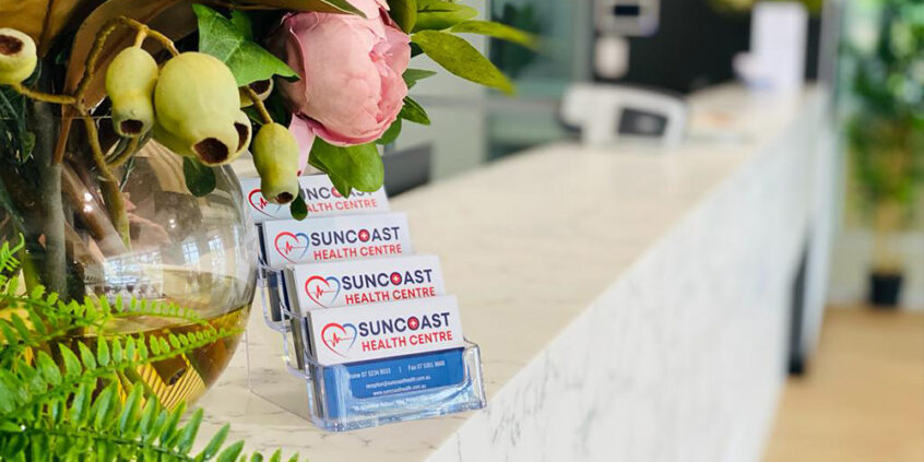 Suncoast Health Centre business cards sitting on reception desk with flowers