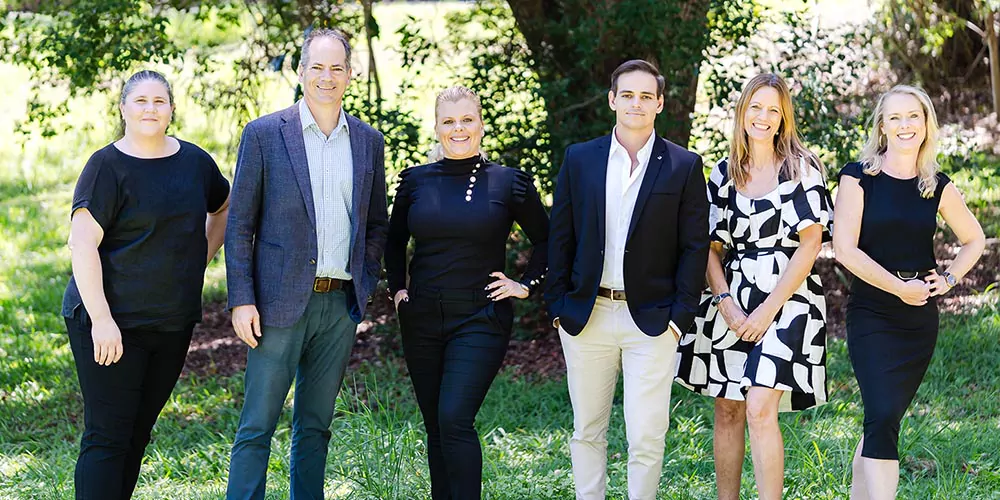 Trish, Dan, Kylie, Dale, Jo and Tracey from The Agency Sunshine Coast standing outside.